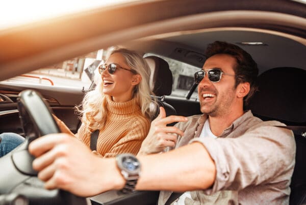 Keep Your Umbrella Handy - Happy Couple in Car on Road Trip Smiling at Each Other