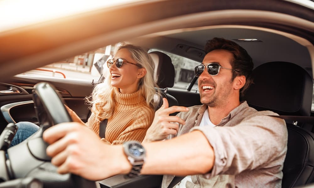 Keep Your Umbrella Handy - Happy Couple in Car on Road Trip Smiling at Each Other